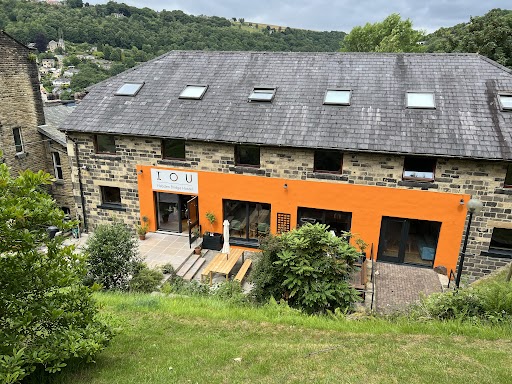 http://There%20is%20a%20large%20stone%20building,%20with%20a%20bright%20orange%20panel%20on%20the%20front.%20There%20are%20trees%20in%20the%20background,%20and%20a%20blue%20sky%20above%20the%20trees.