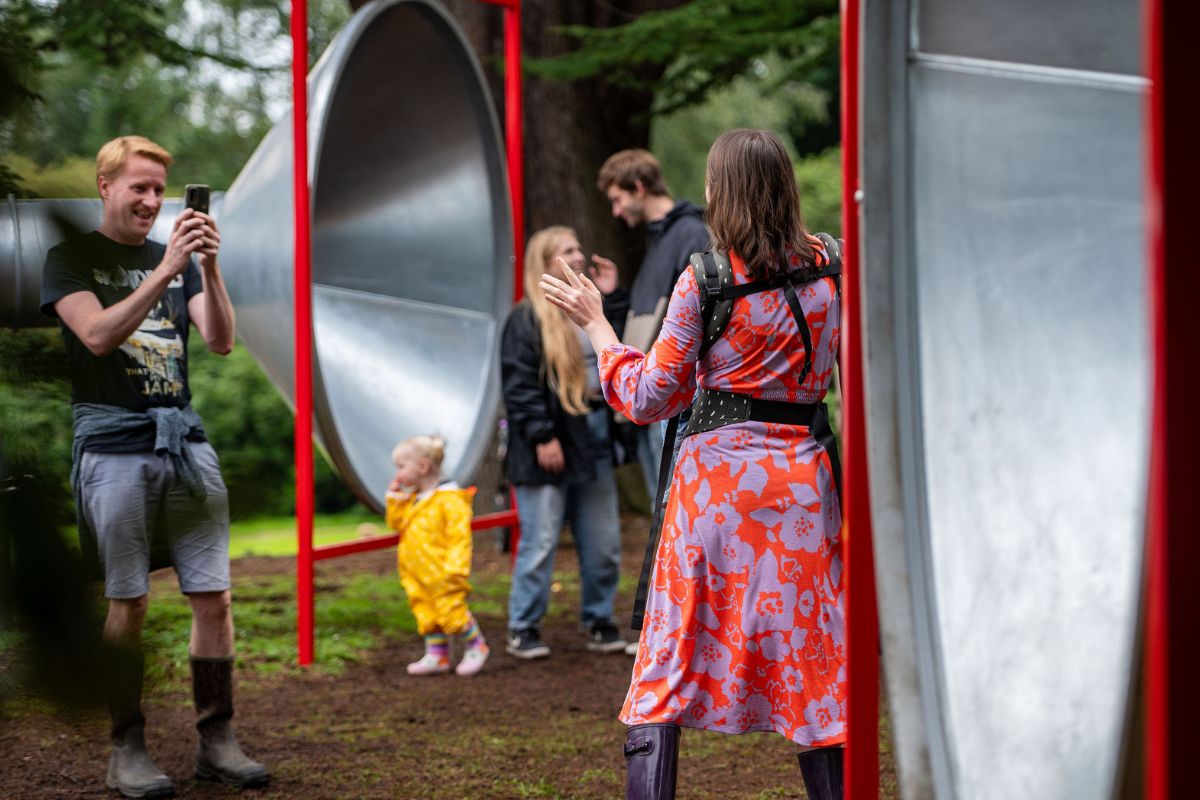 Group of people inc a toddler dance in front of large silver tubes